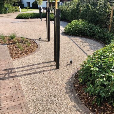 Curved pathway lined with green plants and fitness poles.